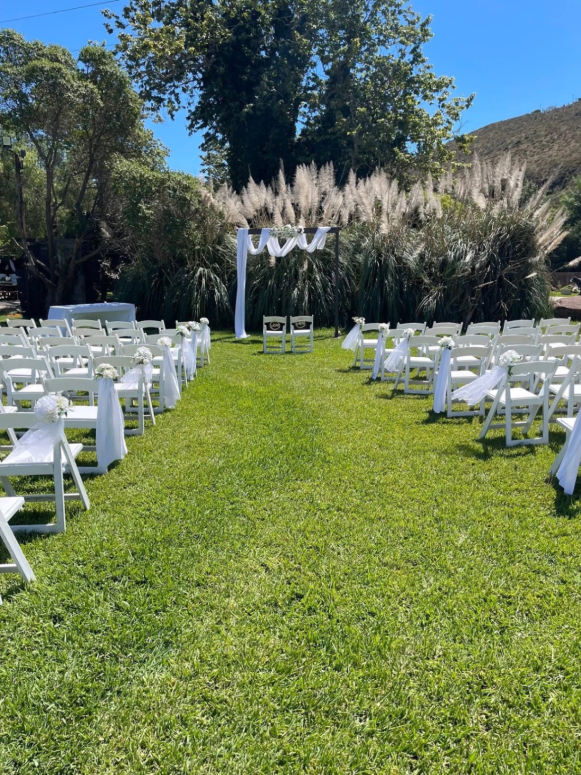 Ceremonia al aire libre con sillas blancas y arco